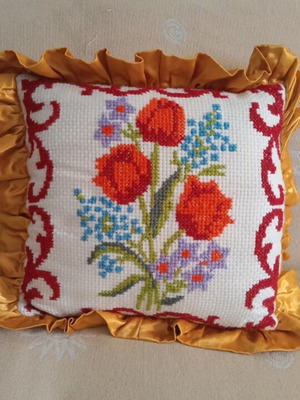 Embroidered pillow handmade with floral cross-stitch and gold ruffle