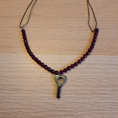 Necklace with black cord, burgundy polygonal beads and hematite key pendant like new