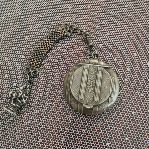 Silver powder compact used, 1880 era with chain and embossed figures