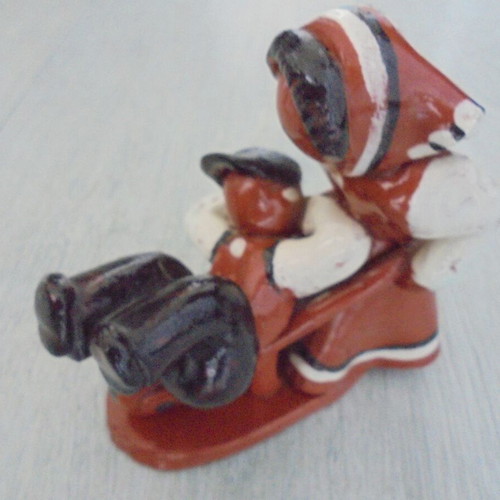 Ceramic figure used, retro genre scene woman pushing man in cart