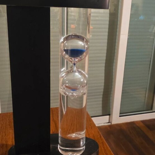 Decorative hourglass with blue sand, black wooden base