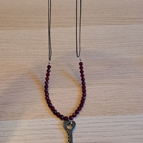 Necklace with black cord, burgundy polygonal beads and hematite key pendant like new