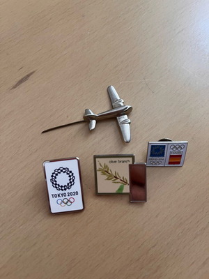 Collectible pins from Tokyo 2020 and Athens 2004 with silver airplane