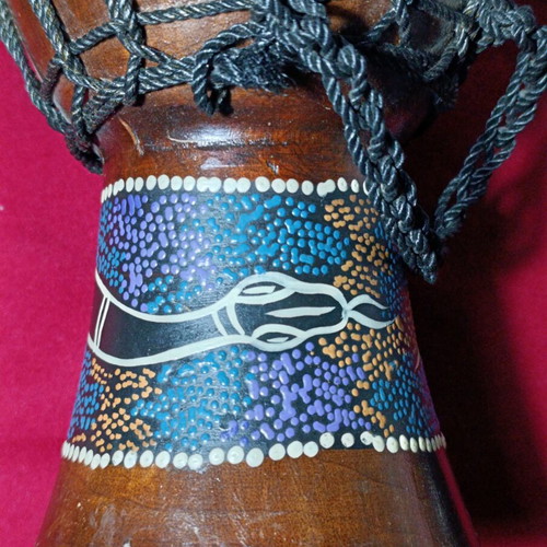 Djembe drum used with hand-painted snake design and torn skin