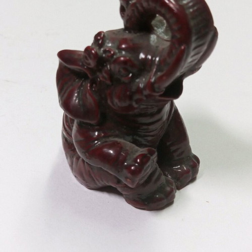 Carved miniature laughing elephant statue like new, burgundy color