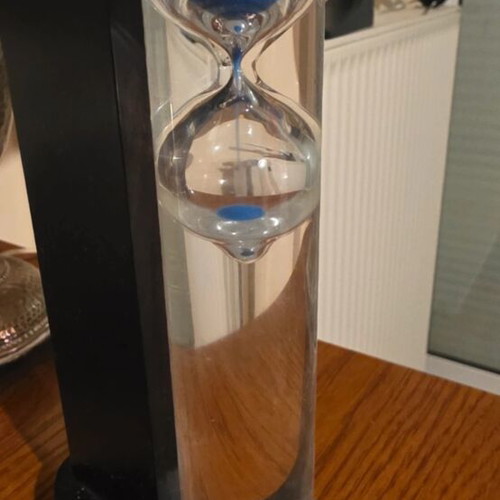 Decorative hourglass with blue sand, black wooden base
