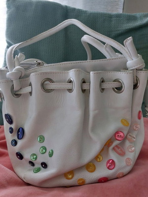 White bucket handbag used with decorative buttons