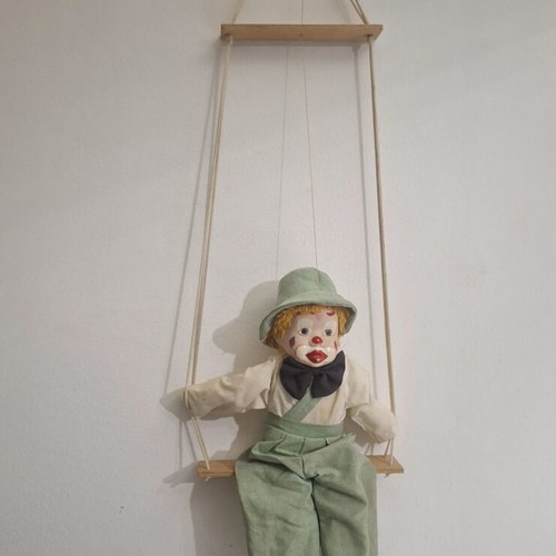 Porcelain clown doll on wooden swing, vintage collectible