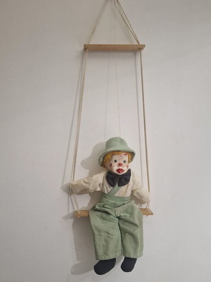 Porcelain clown doll on wooden swing, vintage collectible