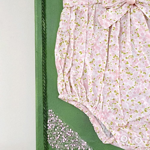 Handmade canvas frame with baby romper, pink flowers, beads, and lace