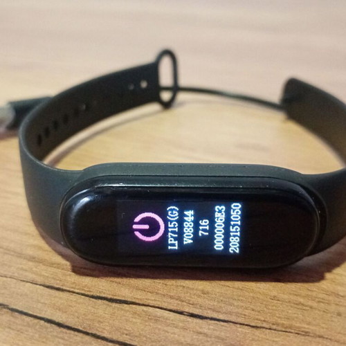 M6 Smart Band fitness tracker used with charging cable