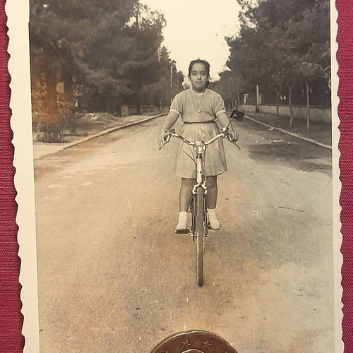 Vintage black and white photo of girl on bicycle with scalloped edge