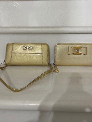 Two gold wallets, one with wrist strap