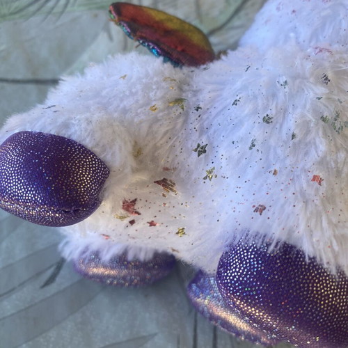 Unicorn plush toy with colorful shiny wings and metallic purple details