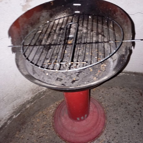 Portable vintage charcoal barbecue with red central leg, used