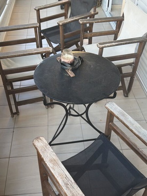 Εξωτερικό στρογγυλό σιδερένιο τραπεζάκι με τέσσερις μεταχειρισμένες καρέκλες σκηνοθέτη