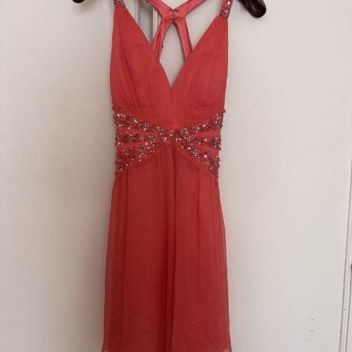 Coral short evening dress with crisscross straps, V neckline, and shiny embroidered beads