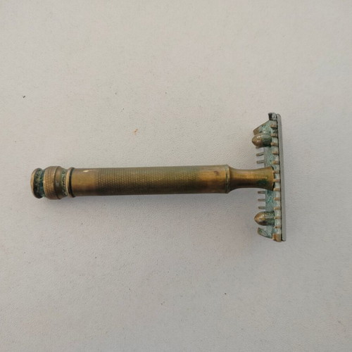 Vintage brass razor used with visible wear and oxidation