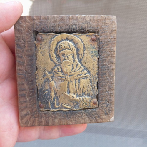 Old brass icon of Saint Anthony in carved wooden frame, used