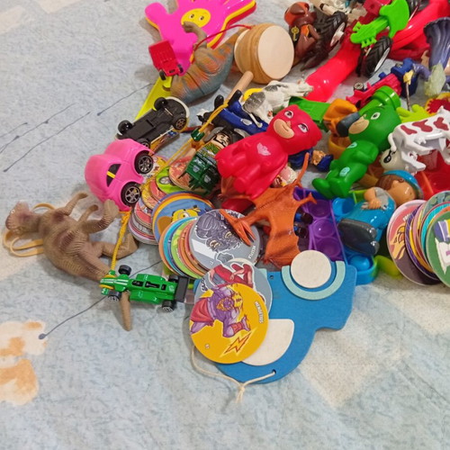 Box of various used children's toys including pop-it and wooden drum