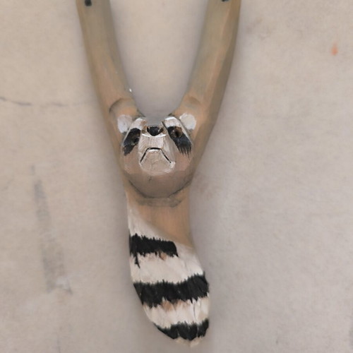 Handmade wooden slingshot with carved raccoon