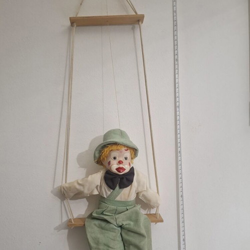 Porcelain clown doll on wooden swing, vintage collectible