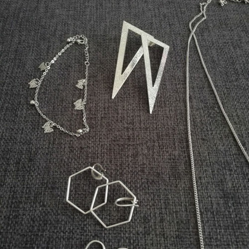 Various silver jewelry including earrings, body chain, rings, and necklace