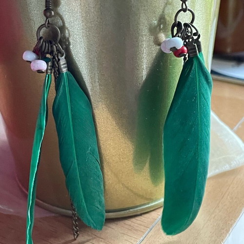 Handmade earrings used with green feathers and multicolored beads