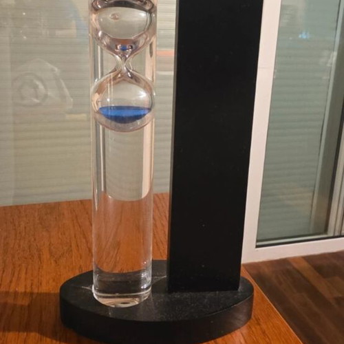 Decorative hourglass with blue sand, black wooden base