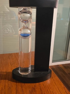 Decorative hourglass with blue sand, black wooden base