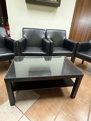 Waiting room furniture set with four black synthetic leather armchairs and glass coffee table