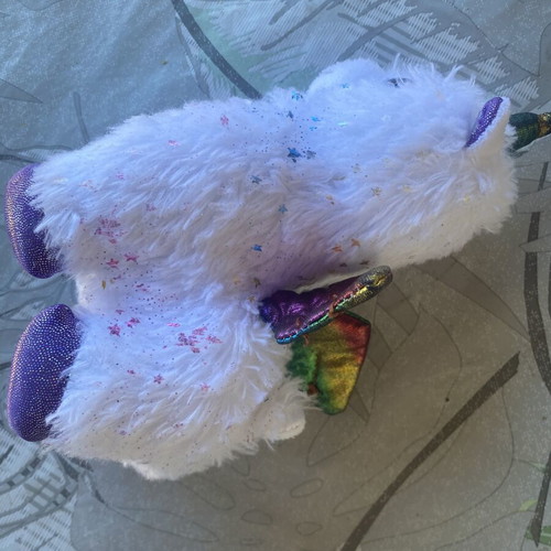 Unicorn plush toy with colorful shiny wings and metallic purple details