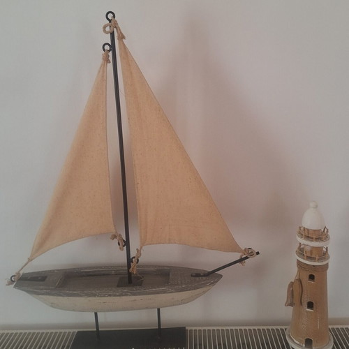 Decorative wooden sailboat with fabric sails and wooden lighthouse used
