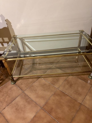 Metal coffee table with gold finish and glass shelves