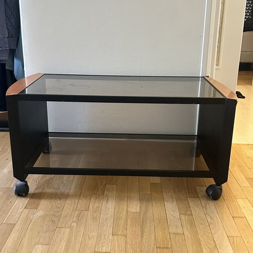 Coffee table with glass top, black metal frame and wooden corners