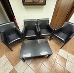 Waiting room furniture set with four black synthetic leather armchairs and glass coffee table