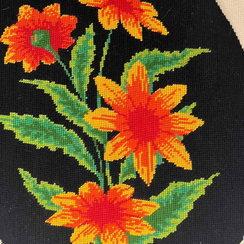 Handmade embroidery with orange daisies on black background used