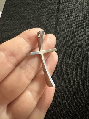 Silver cross pendant with modern curved design, glossy finish