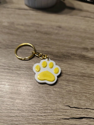 Handmade paw-shaped keychain with yellow embossed details
