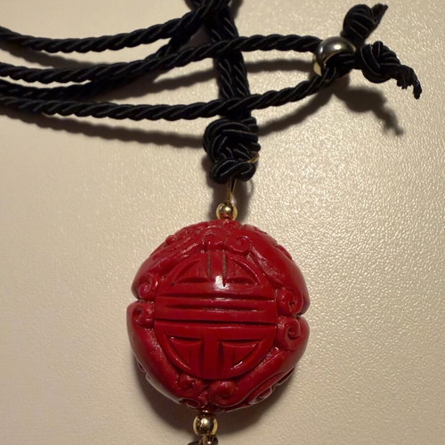 Long pendant like new with red carved bead and black fabric cord
