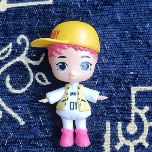 Doll figure with yellow cap and pink hair