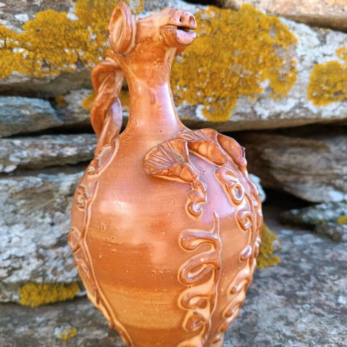 Handmade ceramic jug used with animal-shaped neck and embossed floral designs