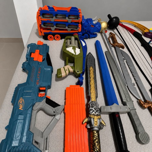 Children's toy weapons set including nerf guns, swords, bows, and truck race track