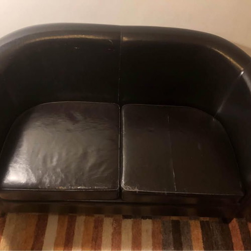 Two-seater black faux leather sofa used with some cushion wear