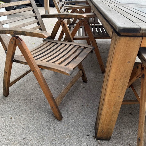 Outdoor table with 8 used teak chairs and black stone