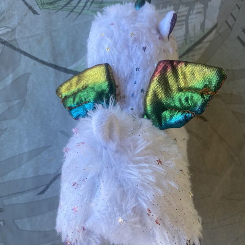 Unicorn plush toy with colorful shiny wings and metallic purple details