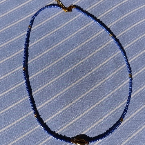 Necklace new made of steel wire with blue and gold glass beads and gold-plated shell