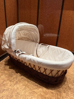 Baby bassinet with woven wicker base and hood