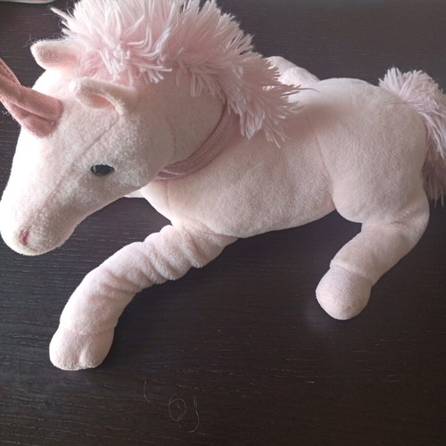 Pink plush unicorn toy used in lying position