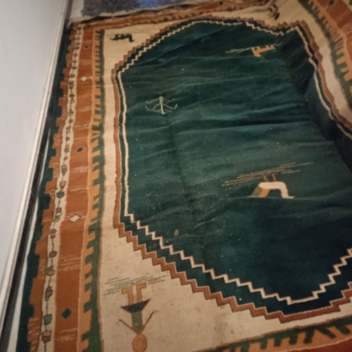 Turquoise machine-made rug used with animal and human designs
